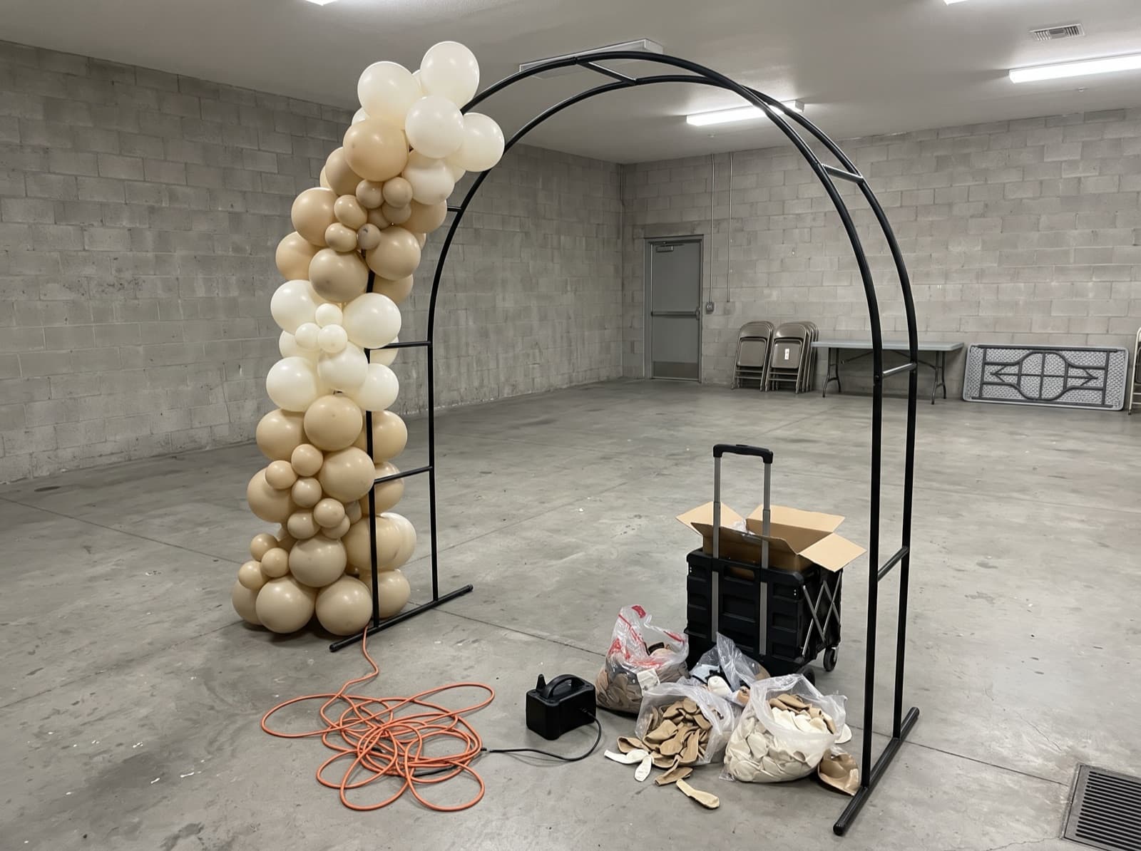 Organic balloon garland half-built on an arch frame before an event
