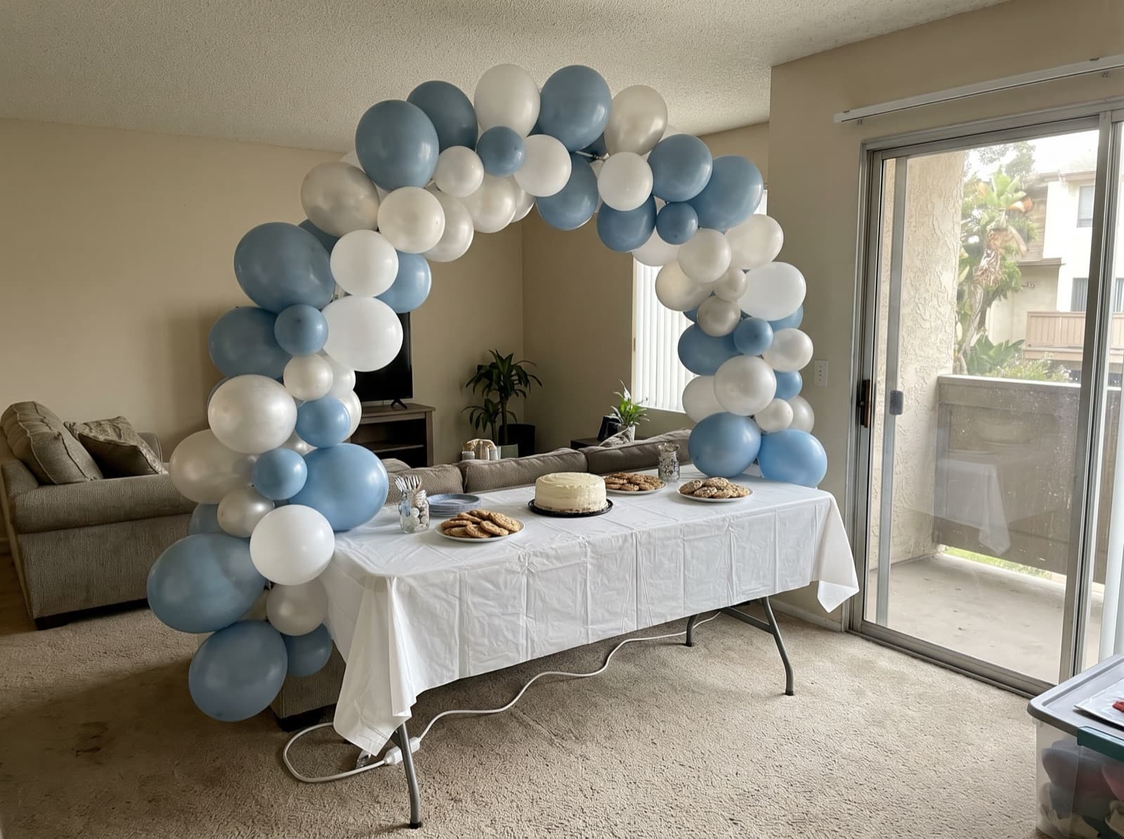 Organic balloon arch in dusty blue, white and pearl over a dessert table
