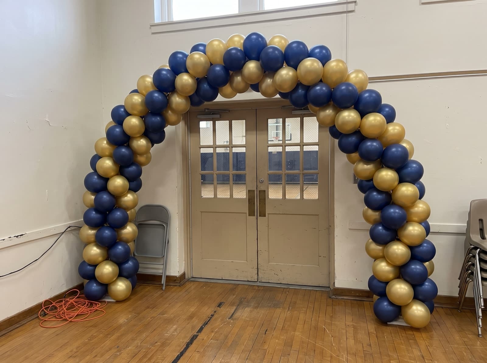 Spiral balloon arch in navy and gold over a school gym entrance