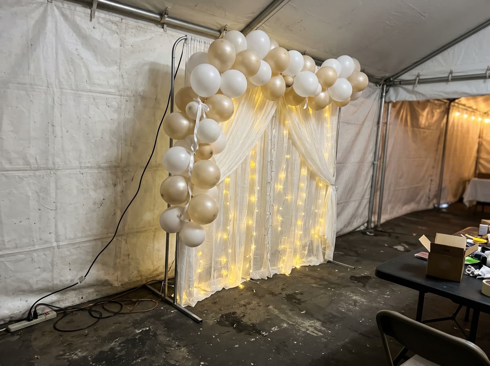 Draped backdrop with balloons and lights in a tent