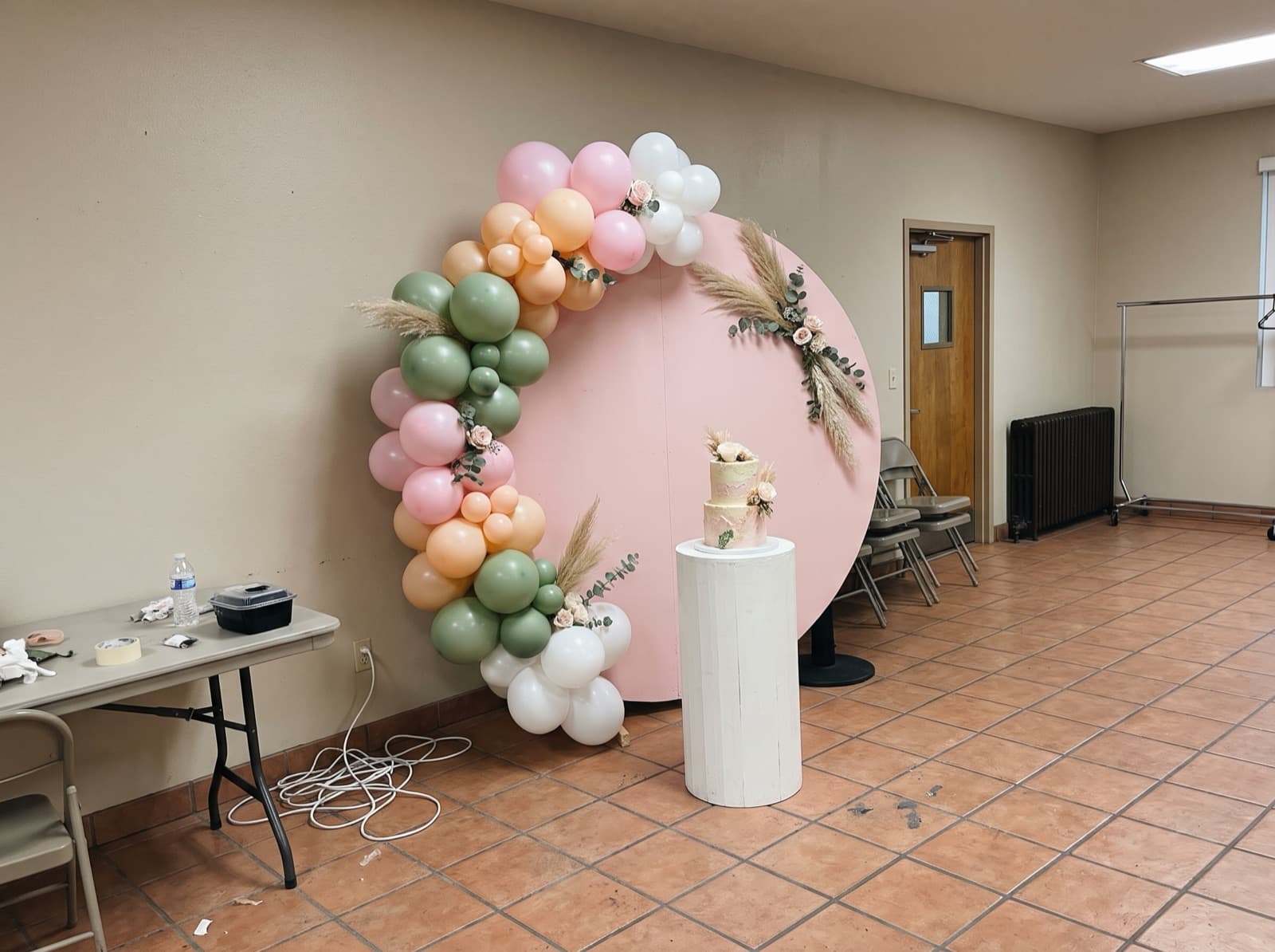 Round pink backdrop with a pastel organic balloon garland