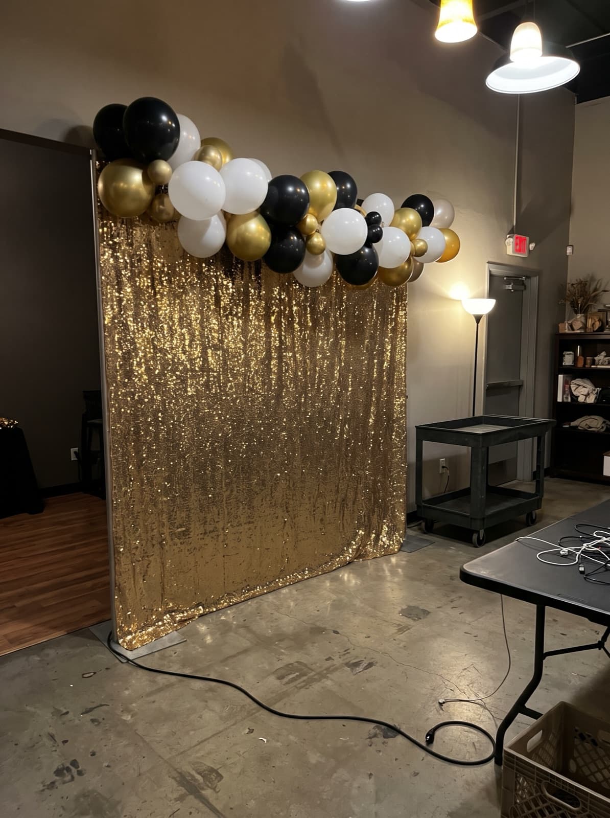 Gold sequin wall with a black, white and gold balloon garland