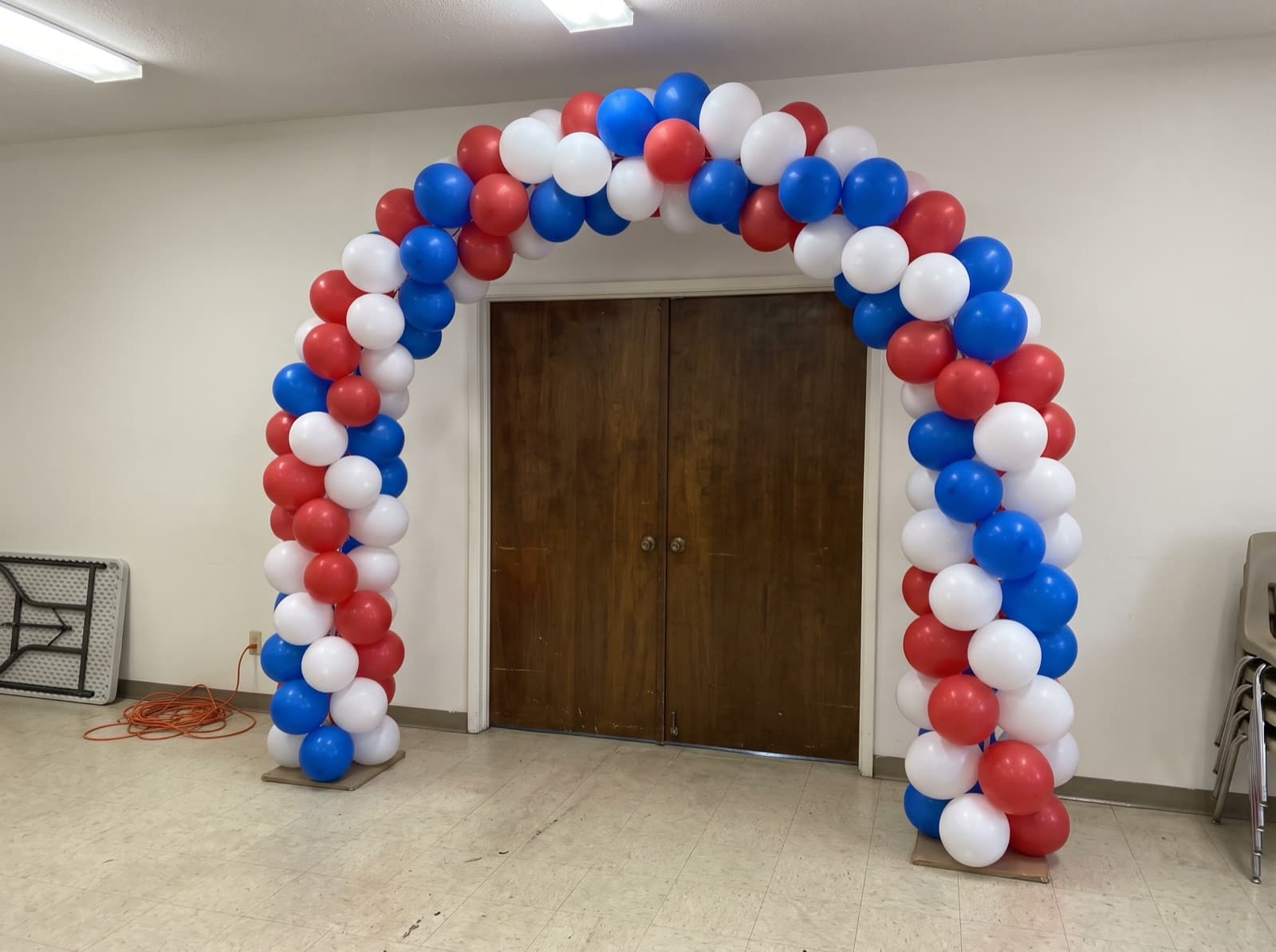 Balloon columns joined by a red, white and blue arch