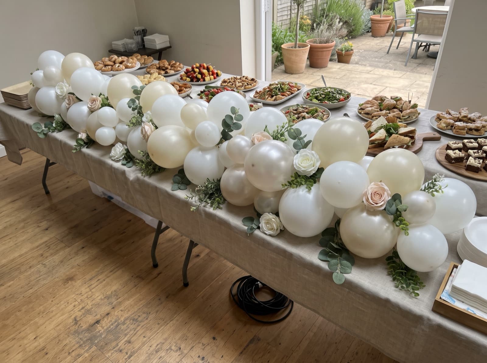 Balloon garland with eucalyptus and silk flowers on a garden buffet