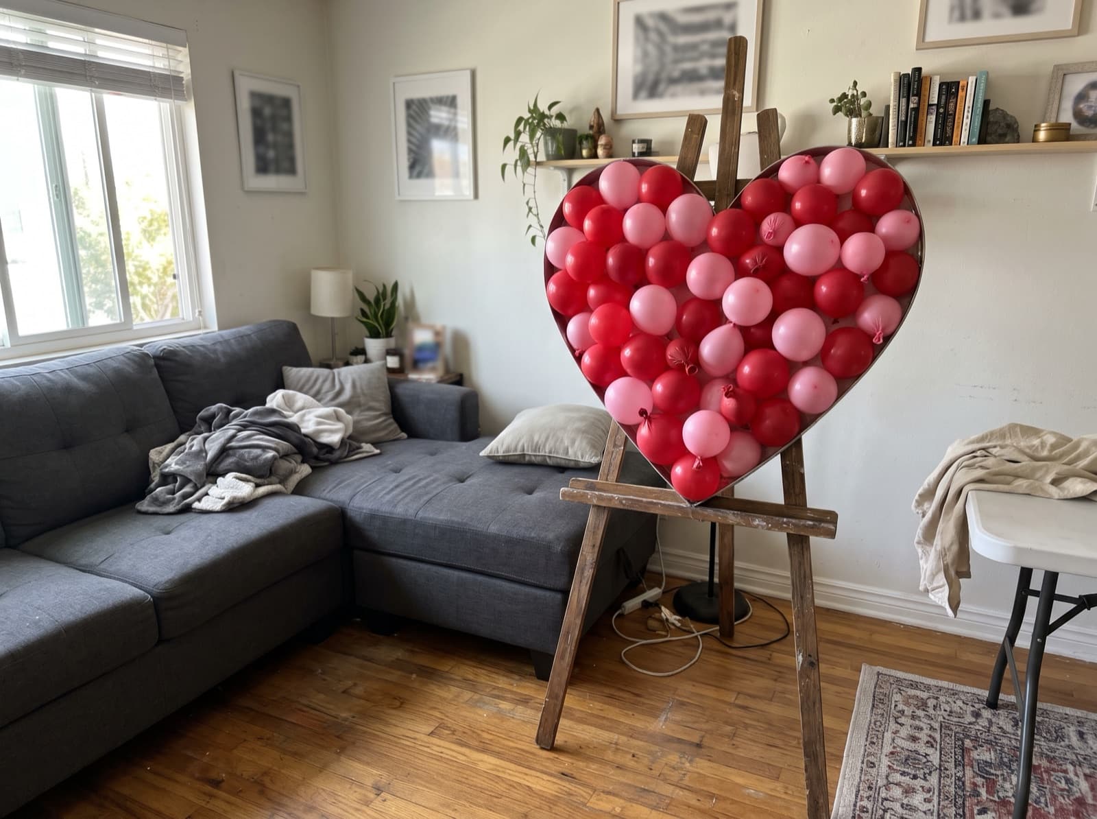 Red and pink heart-shaped balloon mosaic on an easel