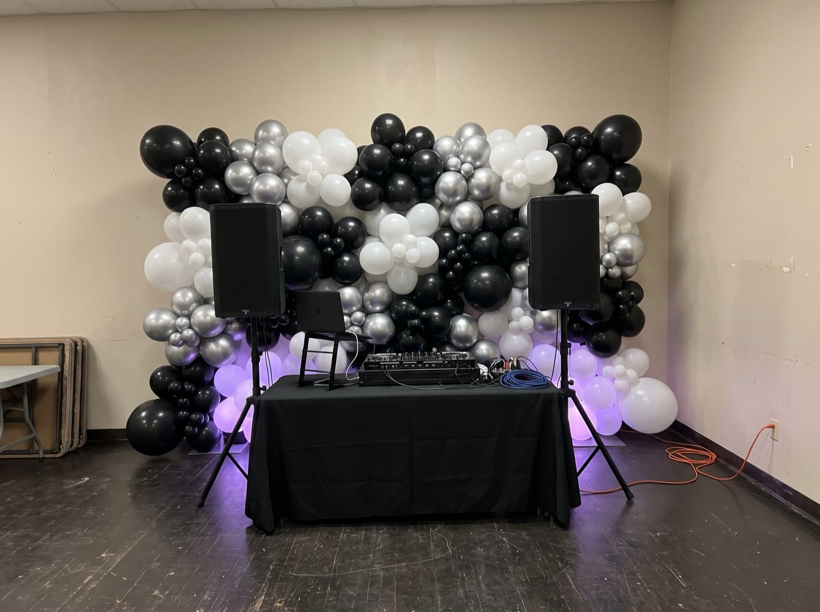 Black, silver and white balloon wall behind a DJ booth