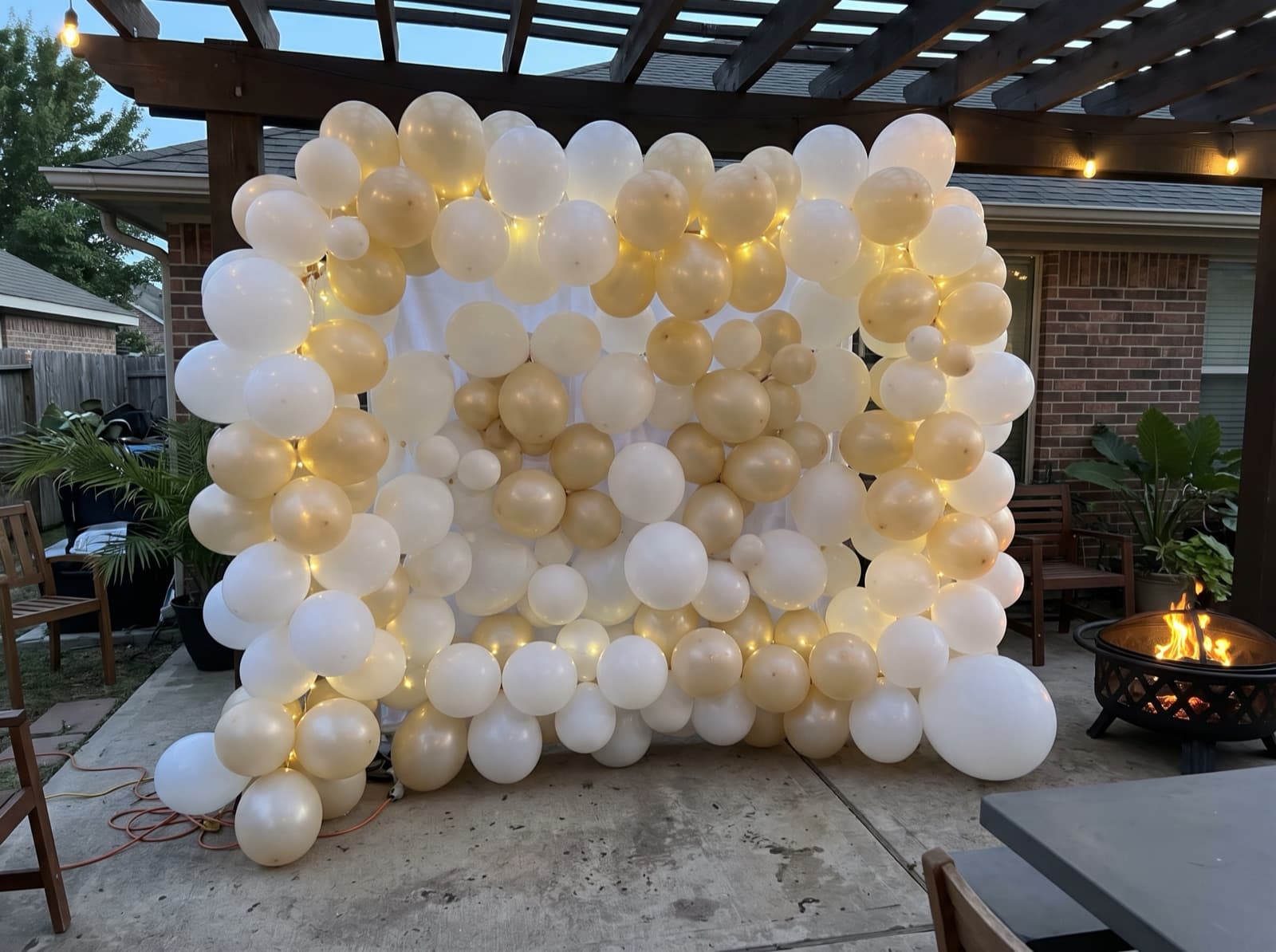 Balloon wall with string lights on an evening patio